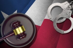 Texas US state flag with judge mallet and handcuffs in dark room.